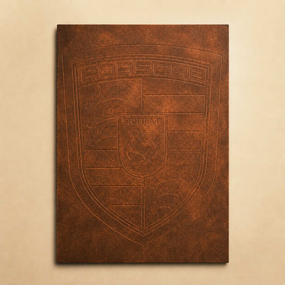 A rectangular brown canvas print featuring an embossed Porsche crest design, displayed against a light beige wall.